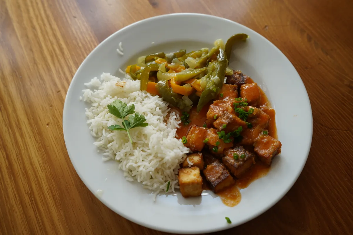 Ein Teller mit Reis, Gemüse und Tofu.